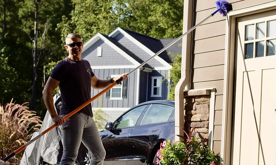 Donnie Shelton sweeping exterior of home for pests