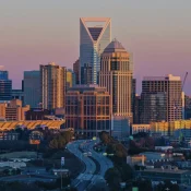 Charlotte skyline at sunset with Bank of America Corporate Center and city buildings glowing in golden light.